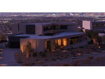 Stunning modern home featuring desert landscaping and illuminated architectural elements for a sleek curb appeal at night at 21 Rockstream Dr, Henderson, NV 89012