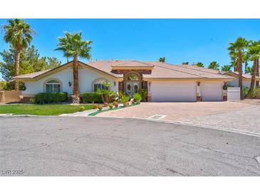 Attractive single-story home featuring a three-car garage, arched entryway, and desert landscaping at 2290 Casa Bella Ct, Las Vegas, NV 89117