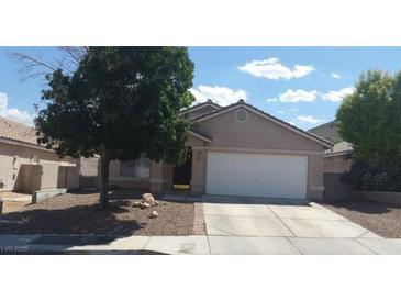 Tan single-story home with a two car garage, desert landscaping and mature shade tree in the front yard at 33 Newburg Ave, North Las Vegas, NV 89032