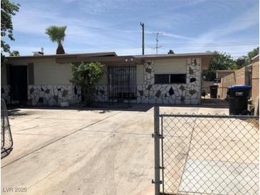 Single-story home featuring stone accents, a secure gated entry and a spacious driveway for multiple vehicles at 725 Miller Ave, North Las Vegas, NV 89030
