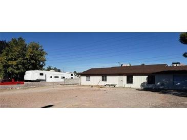 A spacious lot with a white home, some trees, and an RV parked on the side at 7990 Firethorn, Las Vegas, NV 89123