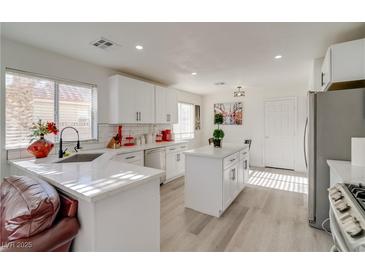 Bright kitchen features white cabinets, subway tile backsplash, and a center island with quartz countertop at 1100 Meridian Bay Dr, Las Vegas, NV 89128