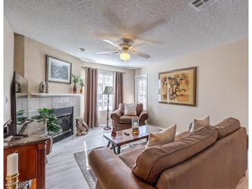 Comfortable living room with a fireplace, ceiling fan, and plush brown leather furniture at 1375 E Hacienda Ave # 114, Las Vegas, NV 89119