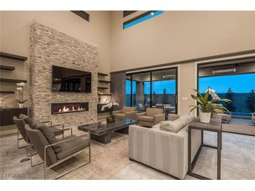 Modern living room with fireplace, stone accent wall, and floor to ceiling windows for seamless indoor/outdoor living at 18 Garden Rain Dr, Las Vegas, NV 89135