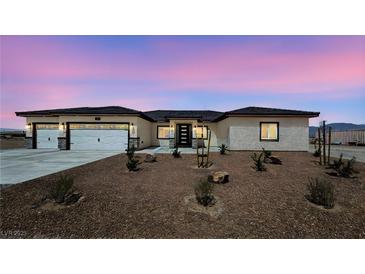 Charming single-story home featuring a three car garage, desert landscaping, and a modern front door at 2900 W Jaybird St, Pahrump, NV 89048