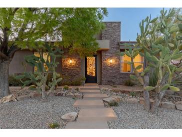 Charming home with a stone facade, desert landscaping, and a decorative iron front door at 48 Panorama Crest Ave, Las Vegas, NV 89135