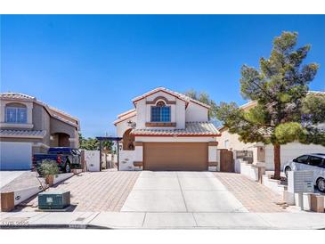 Charming two-story home featuring a brick driveway, two-car garage, and well-maintained landscaping under a clear blue sky at 5325 Sandstone Dr, Las Vegas, NV 89142