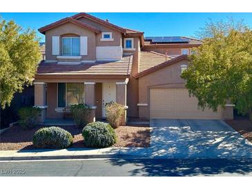Charming two-story home boasts a tile roof, inviting front porch, manicured landscaping, and attached two car garage at 1011 Pecos River Ave, Henderson, NV 89002