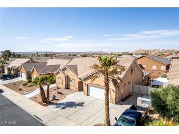 Single-story home with desert landscaping, tile roof, three-car garage, and driveway with desert views at 209 Eucalyptus Ln, Mesquite, NV 89027