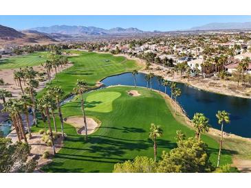 Scenic aerial view of the golf course with palm trees, a lake, and mountain views in the distance at 319 Fox Lake Ave, Las Vegas, NV 89148