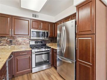 Well-equipped kitchen with stainless steel appliances, tiled backsplash, and stylish wood cabinets at 3225 Casey Dr # 203, Las Vegas, NV 89120