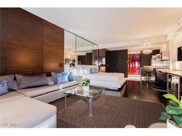 Modern living room featuring a sectional sofa, glass coffee table, and wood-paneled accent wall at 4381 W Flamingo Rd # 1809, Las Vegas, NV 89103