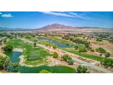 Scenic aerial view of lush golf course with mature trees, serene ponds, and mountain backdrop on a sunny day at 6076 Wheat Penny Ave, Las Vegas, NV 89122