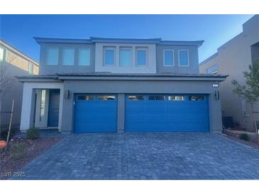 Two-story home featuring a gray exterior and a striking blue two-car garage door, complemented by a paved driveway at 629 Soaring Wings Ave, Las Vegas, NV 89183