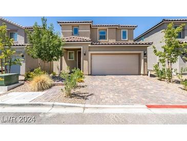 Two-story home features a two-car garage, brick paver driveway, and desert landscaping at 8977 Sweet Chestnut Ln, Las Vegas, NV 89178