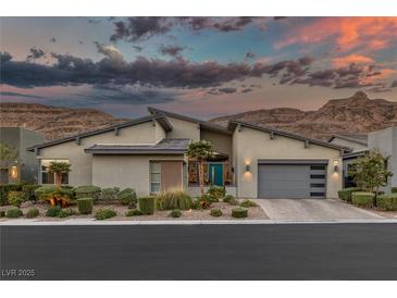 Contemporary home with desert landscaping, blue door and mountains in background at dusk at 10271 Meridian Hill Ave, Las Vegas, NV 89135