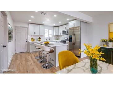 Bright kitchen featuring white cabinets, stainless steel appliances, an island with seating, and modern decor at 2621 Bello Dr, North Las Vegas, NV 89030