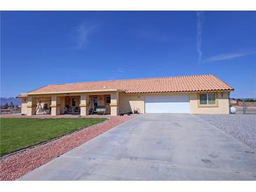 Charming single-story home featuring a vibrant lawn, long driveway, and a terracotta-colored tiled roof at 3110 National Ave, Pahrump, NV 89048