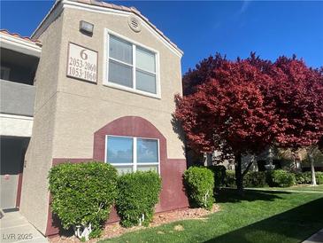 Two-story condo featuring manicured landscaping and red tree at 5055 W Hacienda Ave # 2055, Las Vegas, NV 89118