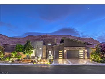 Stunning modern home exterior with a well-manicured yard and mountain backdrop at twilight at 6103 Stone Rise St, Las Vegas, NV 89135