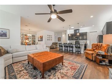 Open-concept living room featuring a large sectional, leather ottoman, and direct access to the kitchen at 715 Orange Plume Walk, Henderson, NV 89011