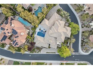 Stunning aerial view of a luxurious home with multiple pools and lush landscaping in an upscale neighborhood at 9 Greely Club Trl, Henderson, NV 89052