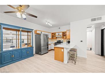 Bright eat-in kitchen features a breakfast bar, stainless steel refrigerator, and blue china cabinet at 5751 Hacienda Ave # 135, Las Vegas, NV 89122