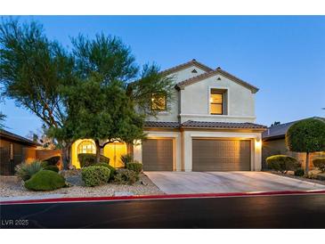Charming two-story home with a two-car garage and meticulously landscaped front yard at dusk at 7416 Redhead Dr, North Las Vegas, NV 89084