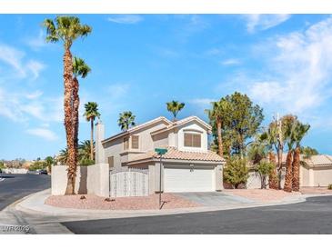 Charming two-story home featuring a tile roof, an attached garage, and well-manicured landscaping with mature palm trees at 125 Firecreek Cir, Las Vegas, NV 89107