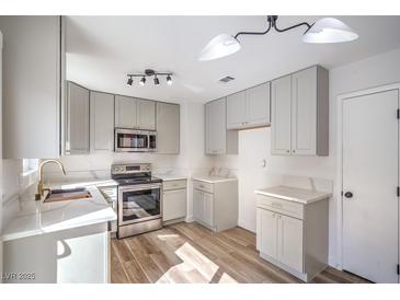 Bright kitchen featuring stainless steel appliances, white countertops, and stylish wood-look flooring at 2727 Scotch Heather St, Las Vegas, NV 89142