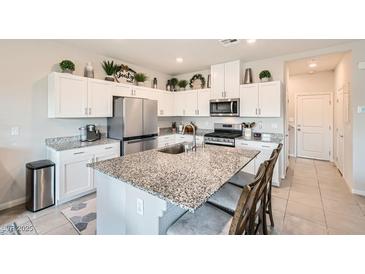 Well-lit kitchen featuring white cabinets, stainless steel appliances, and a granite-topped island with barstool seating at 3903 Ramura Ave, North Las Vegas, NV 89084
