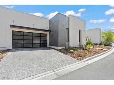 Modern home featuring a unique glass-paneled garage door and desert landscaping at 650 Scenic Cliff Dr, Henderson, NV 89012