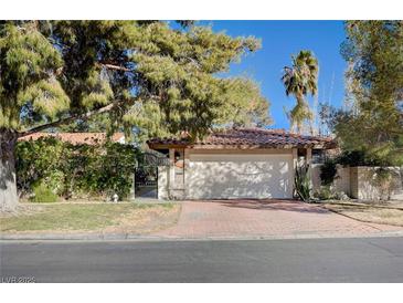 Charming home features a two-car garage, tile roof, mature trees and brick driveway for ample parking at 1905 Calle De Espana, Las Vegas, NV 89102