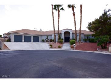 Expansive single-story home showcasing mature palm trees, a 3-car garage, and elegant stone pathway to the front entryway at 2111 Loro Ct, Las Vegas, NV 89117