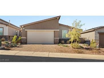 Inviting single-story home with a two-car garage, brick driveway, and desert landscaping at 283 Fossil Falls St, Henderson, NV 89015