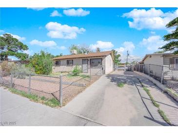 Single story home with a large driveway and fenced yard on a clear day at 916 Putnam Ave, North Las Vegas, NV 89030