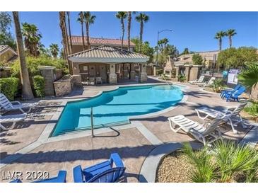 Community pool area with lounge chairs, a covered area and lush landscaping at 6790 Gold Yarrow St, Las Vegas, NV 89148