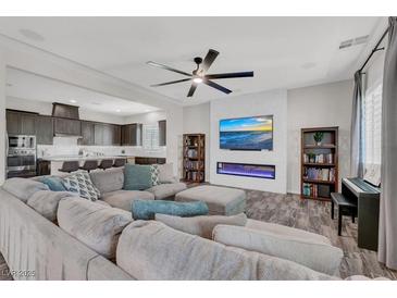 Open-concept living room features a fireplace, entertainment center, ceiling fan and modern decor at 8245 Broad Branch Way, Las Vegas, NV 89113