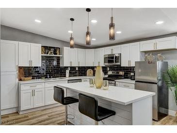 Bright kitchen featuring white cabinets, quartz countertops, black backsplash, and stainless steel appliances at 1660 Izabella Ave, Las Vegas, NV 89169