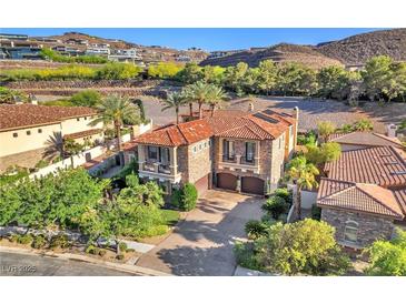 Beautiful stone home featuring a tile roof, balconies, two car garage, and lush landscaping at 1795 Anelli Ct, Henderson, NV 89012