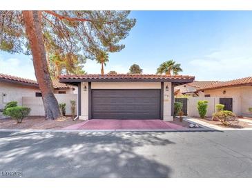Attached two-car garage with a red-tiled roof and neutral paint surrounded by mature trees and shrubs at 2583 Egret Cir, Las Vegas, NV 89121