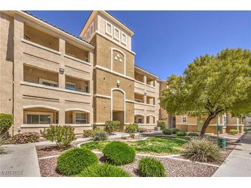Inviting exterior view of condo building with manicured landscaping, shrubs, and mature shade trees at 8777 W Maule Ave # 3102, Las Vegas, NV 89148