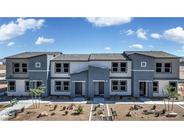 A modern two-story townhome with a gray stucco exterior, well-maintained landscaping, and a welcoming entrance at 9427 Jade Mesa St # Lot 34, Las Vegas, NV 89139