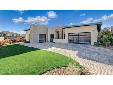 Modern home featuring a brick driveway, turf lawn and two-car garage with translucent glass doors at 12199 Canyon Sunset St, Las Vegas, NV 89138