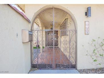 Inviting gated entrance to home with wrought iron gate and desert landscape at 1709 Chapman Dr, Las Vegas, NV 89104