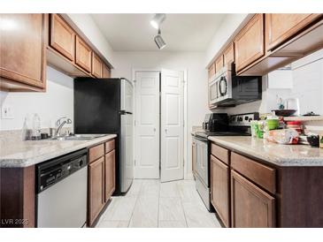 Well-lit kitchen features stainless steel appliances, tile floors, and wood cabinets at 3135 S Mojave Rd # 241, Las Vegas, NV 89121