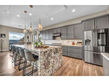 Modern kitchen featuring a large island with granite countertop, stainless steel appliances, and gray cabinetry at 19 Hilltop Crest St, Henderson, NV 89011