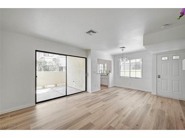 Bright living room featuring light wood floors, a sliding glass door, and modern light fixture at 4855 S Torrey Pines Dr # 101, Las Vegas, NV 89103