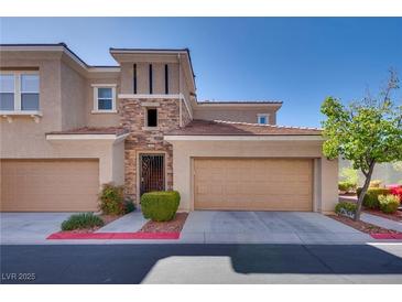 Charming townhome featuring a stone accent wall, well-kept landscaping, and two-car garage at 10809 Garden Mist Dr # 2050, Las Vegas, NV 89135