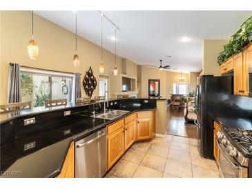 Open kitchen features granite countertops, tile floors, stainless steel appliances, and pendant lighting at 115 Cora Hills Ct, Las Vegas, NV 89148